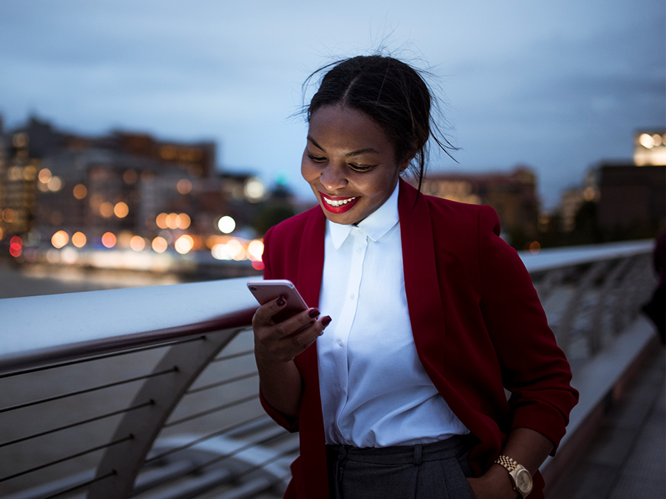 A woman walks at dusk while looking at her phone