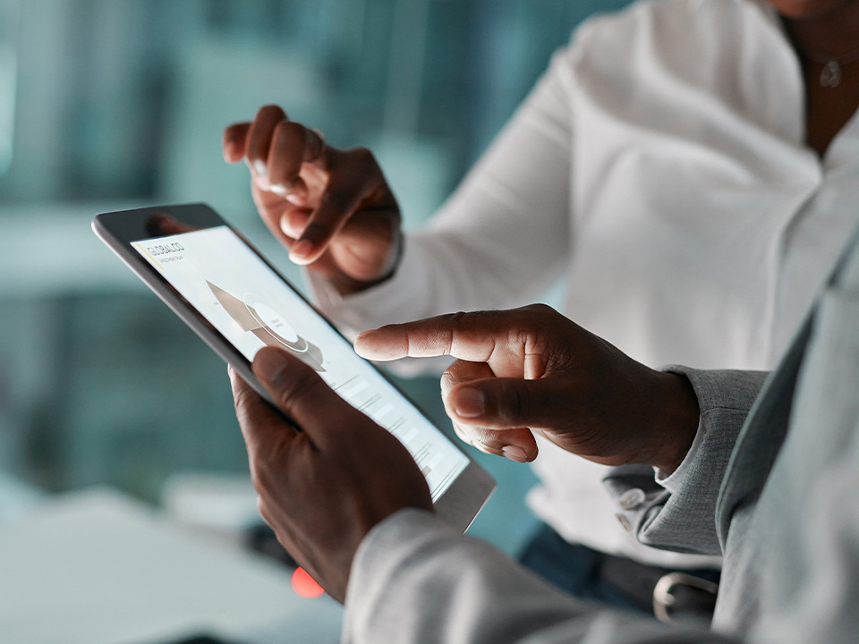 A close up of two people's hands point at a tablet