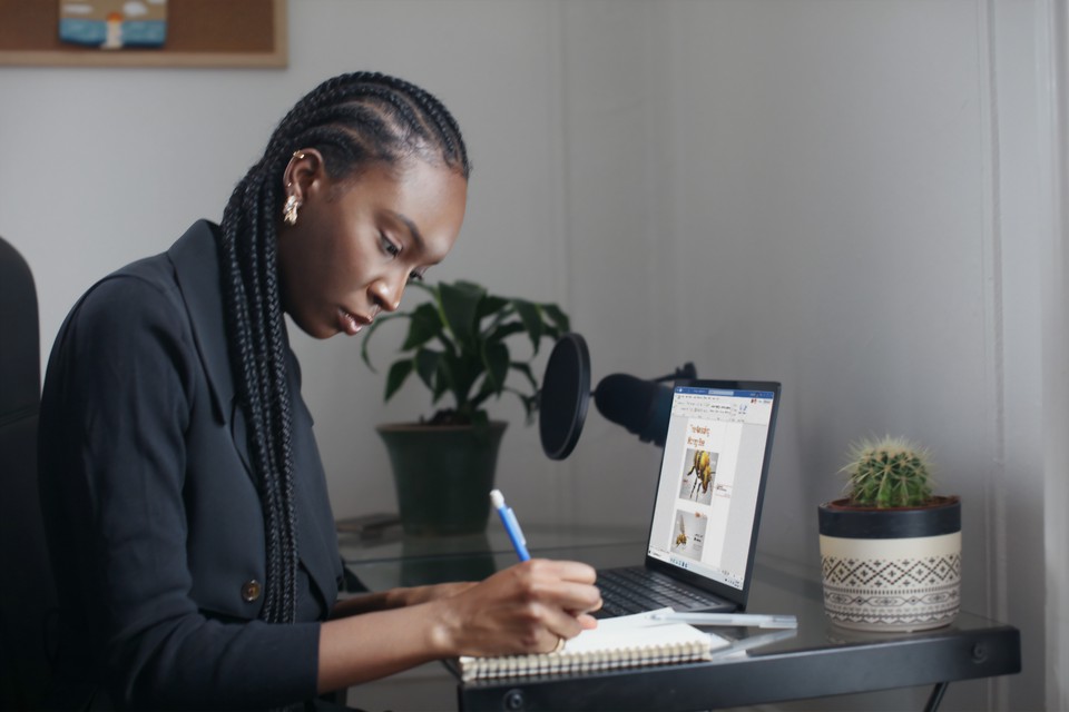 Woman at desk, writing in notebook.