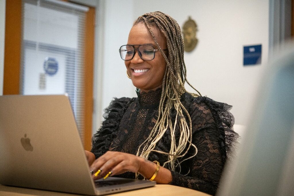 A smiling Howard business student works at a laptop computer.