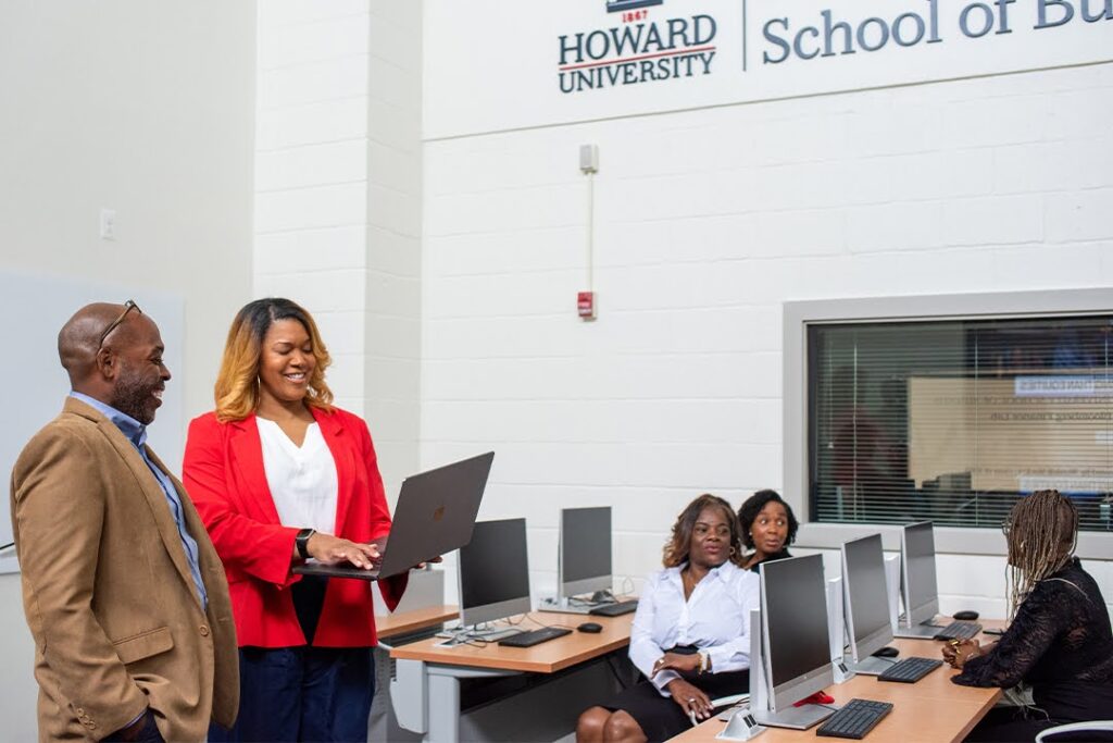 Dr. Curtis Kidd converses with students in a computer lab.